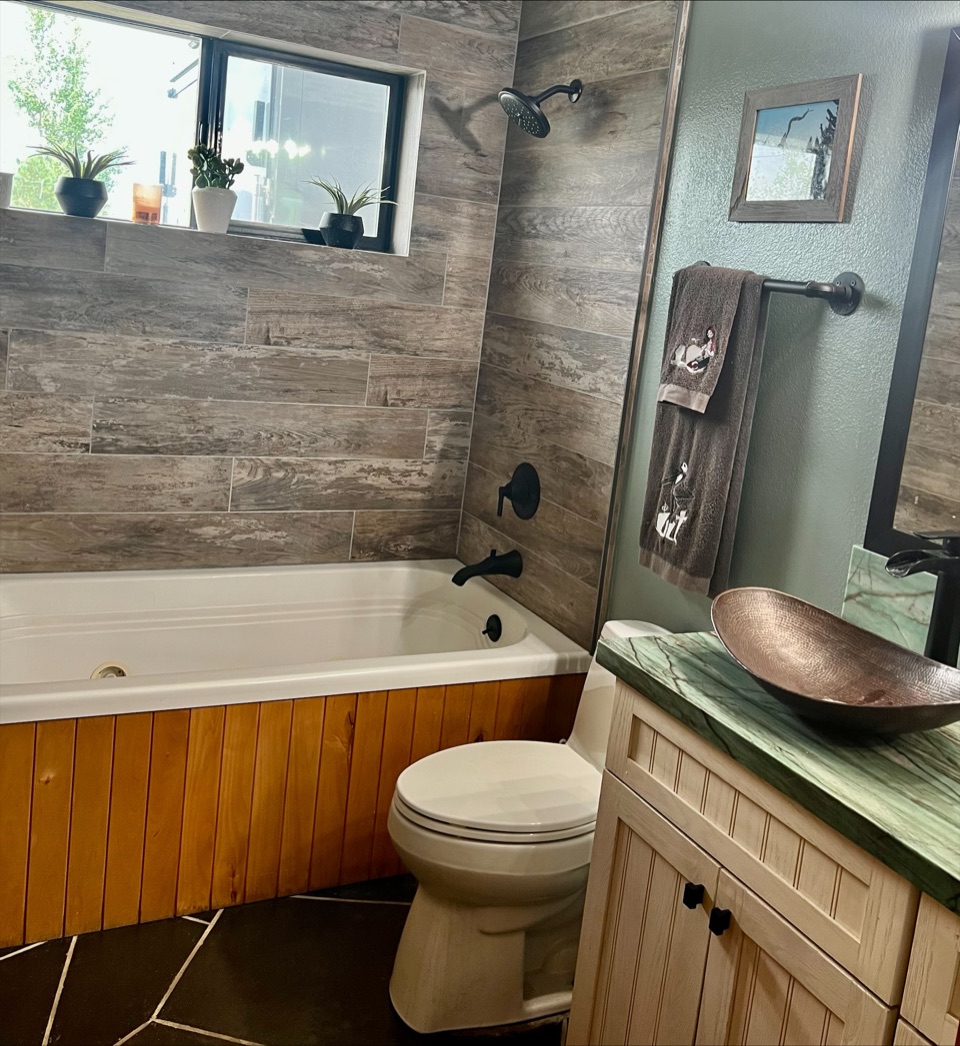Bathroom with wood-look plank tile, a hammered copper vessel sink and a green stone counter