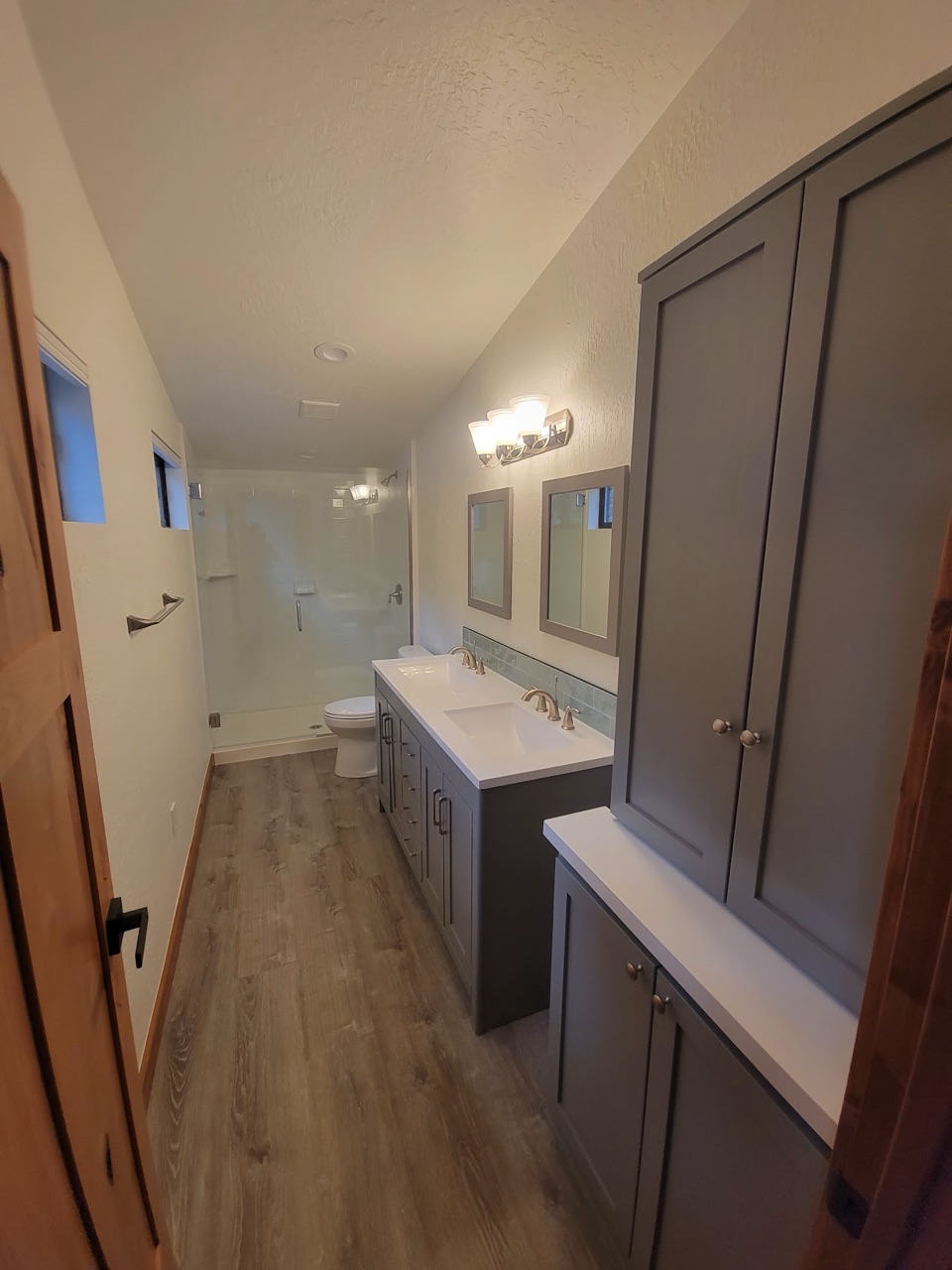 Bathroom with a grey double vanity, quartz top and a glass corner shower