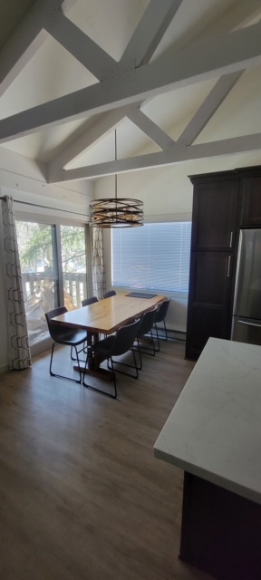 Dining area under a vaulted ceiling with exposed painted scissor trusses and a drum chandelier