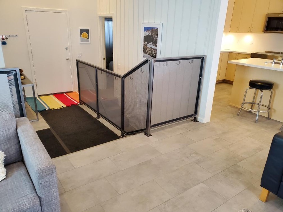 Entry landing with a custom steel-frame mesh railing opening onto a tiled living space