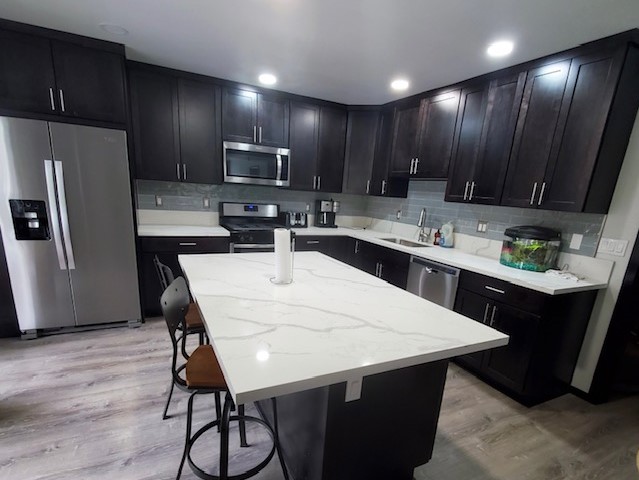 Kitchen with espresso shaker cabinets, veined white quartz counters and a grey glass backsplash