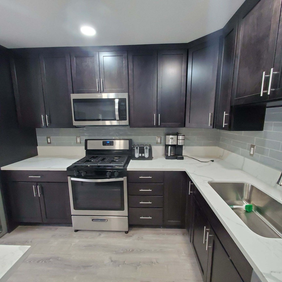 Kitchen with espresso shaker cabinets and veined white quartz counters wrapping to a stainless sink