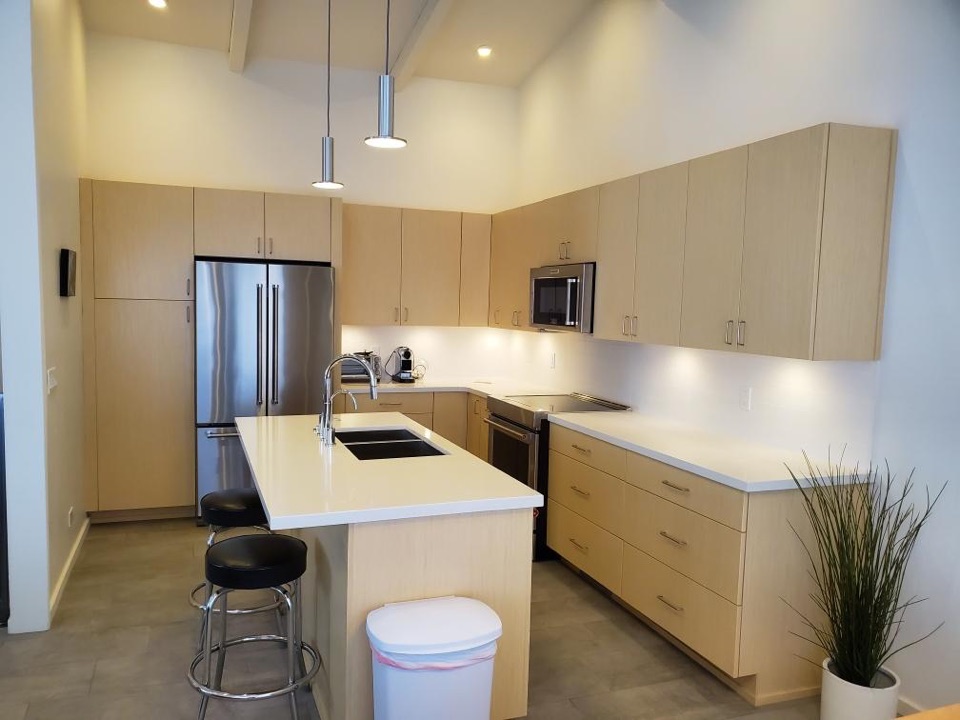 Maple kitchen under a vaulted ceiling with an exposed painted beam and a quartz island