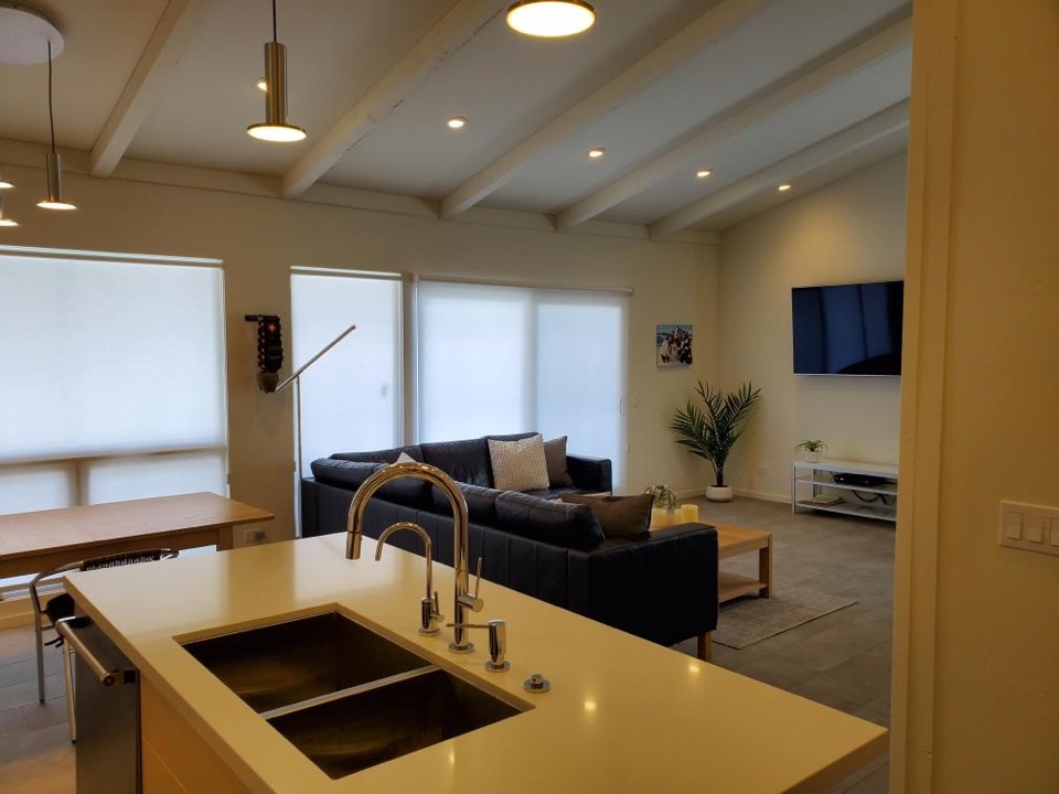 Open-plan kitchen and living room with painted exposed beams and a quartz island