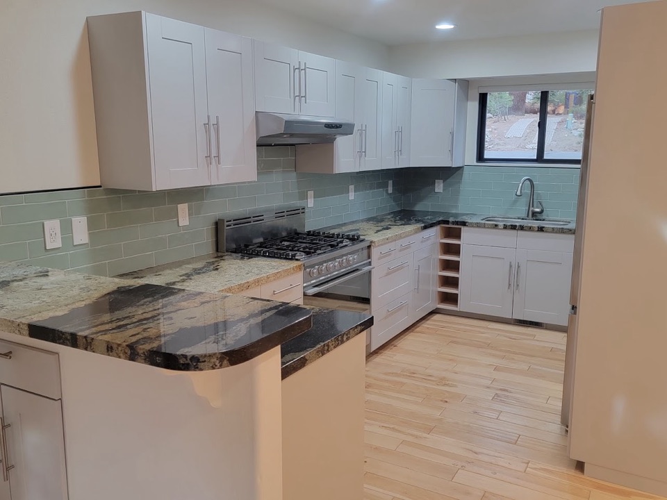 Remodelled kitchen with white shaker cabinets, granite counters and a sea-glass tile backsplash