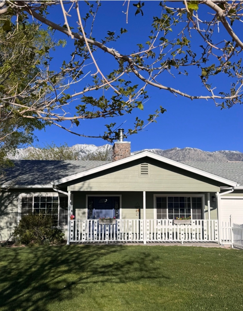 Repainted ranch house with sage green siding and white trim, the snow-capped Sierra crest directly behind it